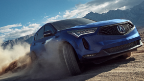 3/4 front view of blue RDX driving on dirt road